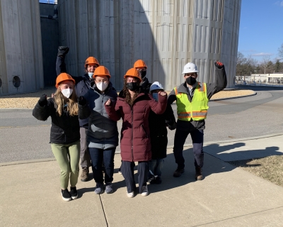 group of students in hard hats and masks in front of water treatment facility