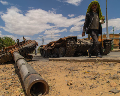 Elderly man walking past destroyed military tank