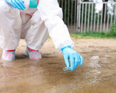 Scientist in protective suit collecting water in test tube