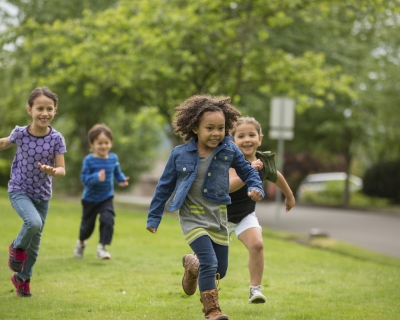 Four kids running and playing on the grass