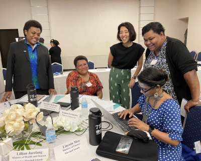 A group of smiling people around a table covered with papers