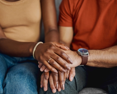 image from neck down of two adults holding hands