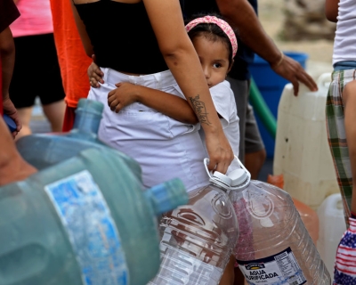 A young girl waits in line for not potable water delivered by a tanker truck in Colonia Mirador de Garcia, northwest of Monterrey, Mexico. July 19, 2022.