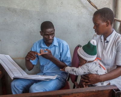 A health surveillance assistant talks to a mother at a malaria vaccine screening table in Lilongwe, Malawi, April 23, 2019.