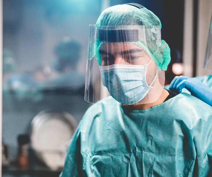 Doctors and nurse preparing to work in hospital for surgical operation during coronavirus pandemic outbreak - Medical workers getting dressed inside clinic - Focus on right man face by DisobeyArt